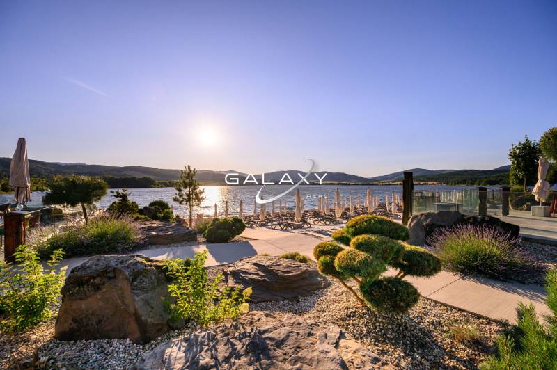 Garden by the water in Ružiná with a view of the lake and sun loungers at sunset.