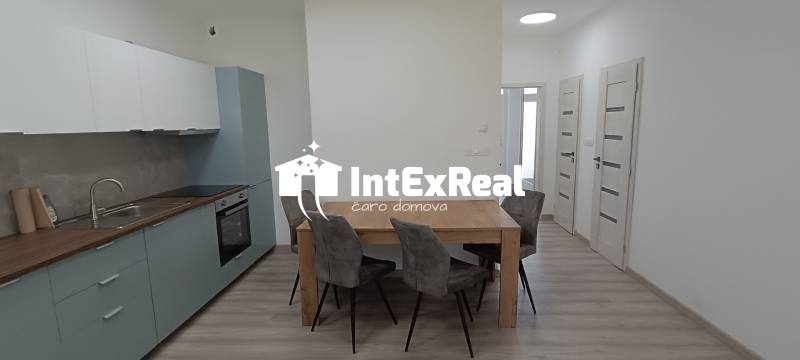 A kitchen and dining area with a wooden table and four chairs in a 2-room apartment.