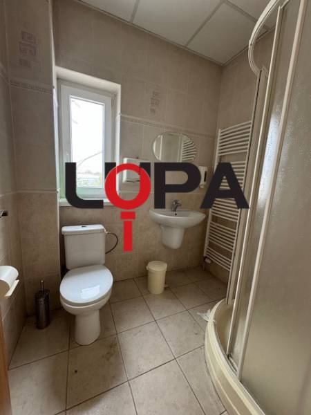 Bathroom in commercial premises with sanitary facilities, shower, and window for natural light.