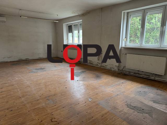 An abandoned room in a building with a wooden floor and large windows.