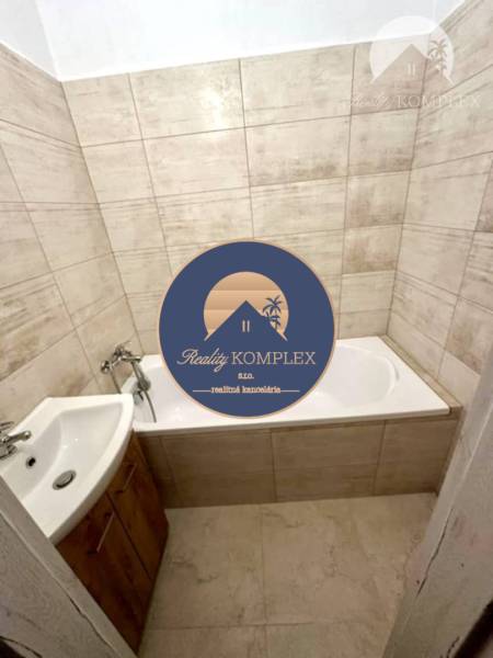 Bathroom in a 2-room apartment with a bathtub and a sink, tiles in beige shades.