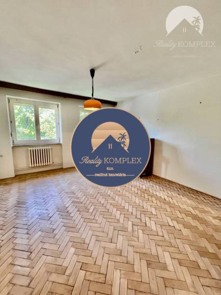 A bright living room in a two-room apartment with a parquet floor and a large window.