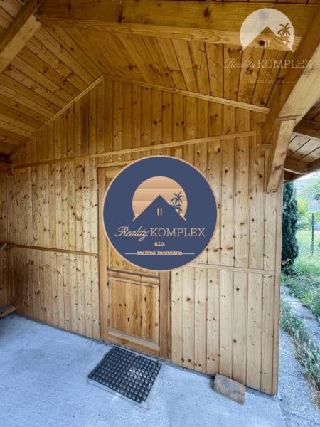 A wooden structure with a sloped roof and entrance door, view from the outside.