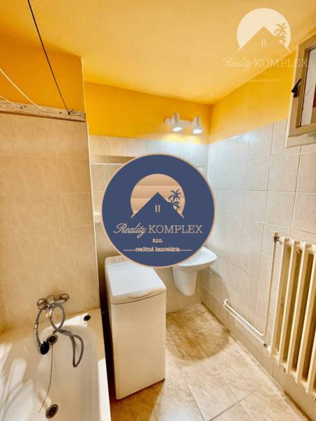 Bathroom with a bathtub, toilet, and washing machine in a 2-room apartment.
