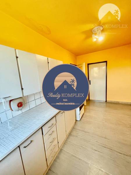 A kitchen in a 2-room apartment with a yellow ceiling, white cabinets, and flooring.