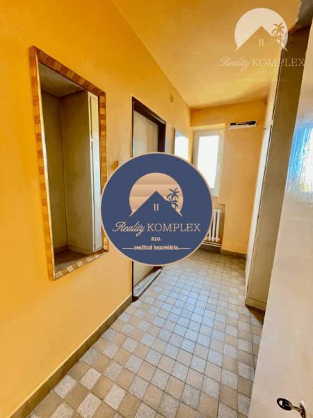 A hallway in a 2-room apartment with a tiled floor and a mirror on the wall.