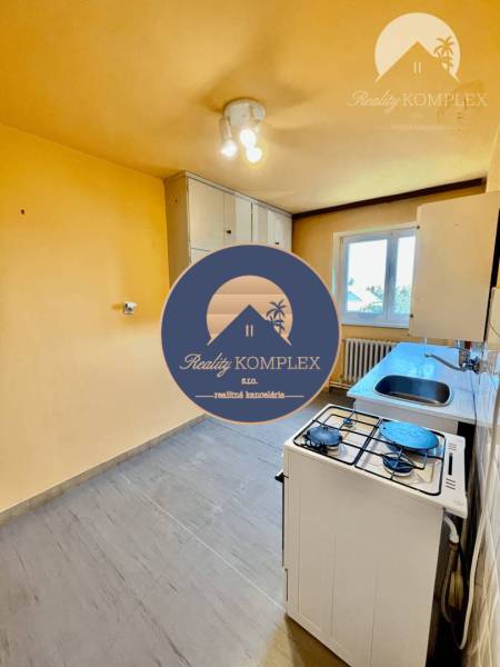 A kitchen in a 2-room apartment with a gas stove, a cupboard, and a window.