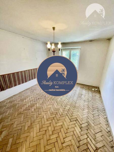 A room in a 2-room apartment with a wooden floor and a chandelier, simple interior.