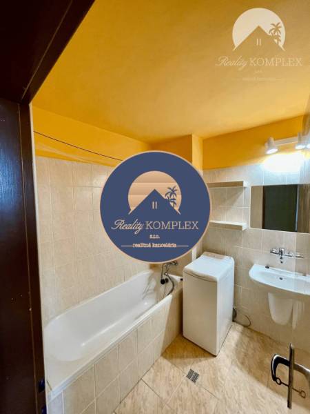 Bathroom in a 2-room apartment with a shower, washing machine, and mirror.