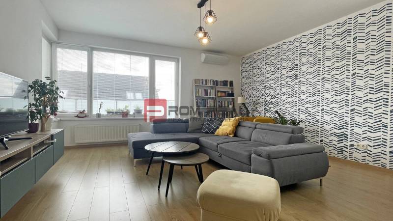 Living room in a two-room apartment with a comfortable sofa, patterned wall, and bookshelf.