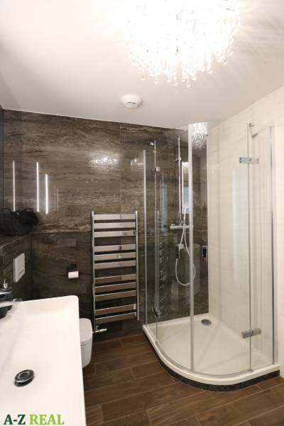 Bathroom with a glass shower enclosure, sink, and chrome ladder in a 3-room apartment.