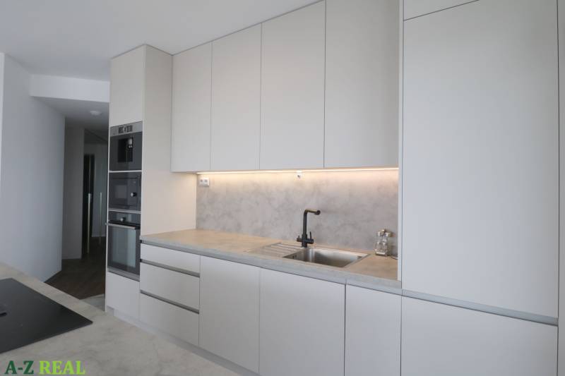A kitchen in a 3-room apartment with white cabinets and built-in appliances.