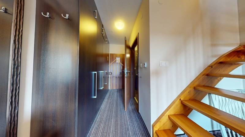 Hallway of a 2-room apartment with built-in wardrobes and a wooden staircase.