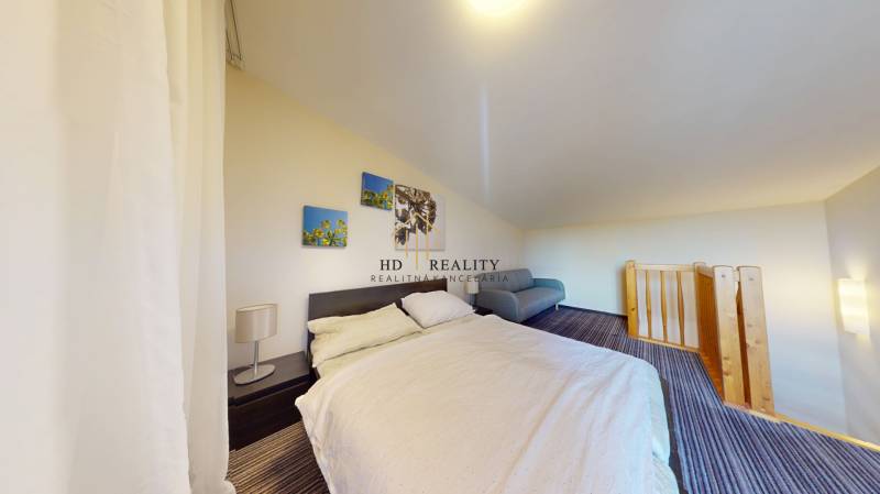 A bedroom in a two-room apartment with a comfortable bed and a railing by the staircase.