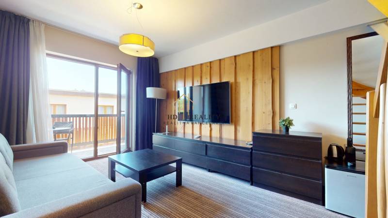 Living room of a two-room apartment with a sofa, TV, and balcony doors.