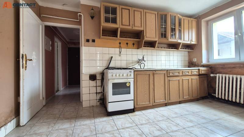 A kitchen unit in a 3-room apartment with a gas stove and tiles on the wall.