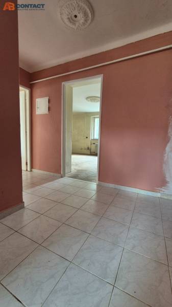 The hallway in a 3-room apartment with white floor tiles and pink walls.