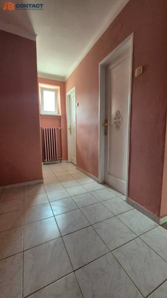 A hallway in a 3-room apartment with tiles, a radiator, and two doors.