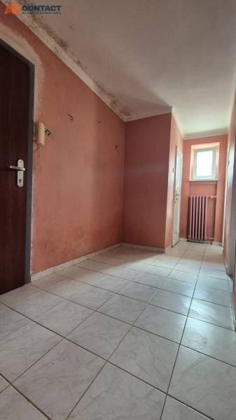 A hallway with light-colored tiles in a 3-room apartment, light pink walls, radiator.