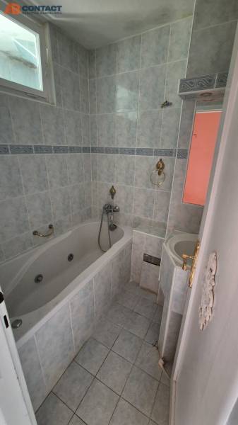 Bathroom in a 3-room apartment with a bathtub, sink, and tiles in muted colors.