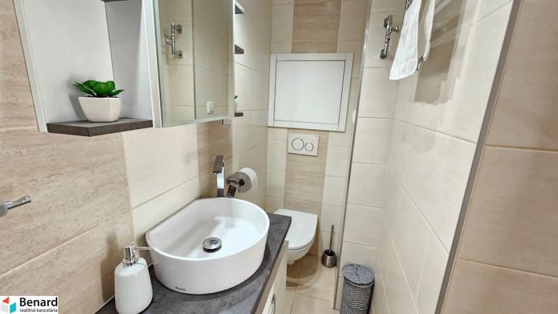 Bathroom in a studio apartment with a sink, mirror, and toilet.