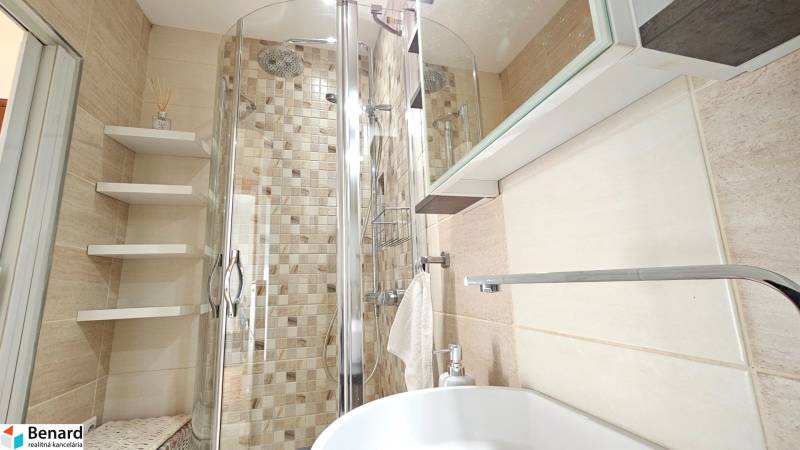 Bathroom in a studio apartment with a modern shower and practical shelves.