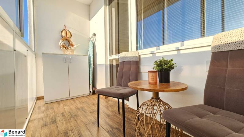 A balcony in a one-room apartment with two chairs, a table, and a storage cabinet.