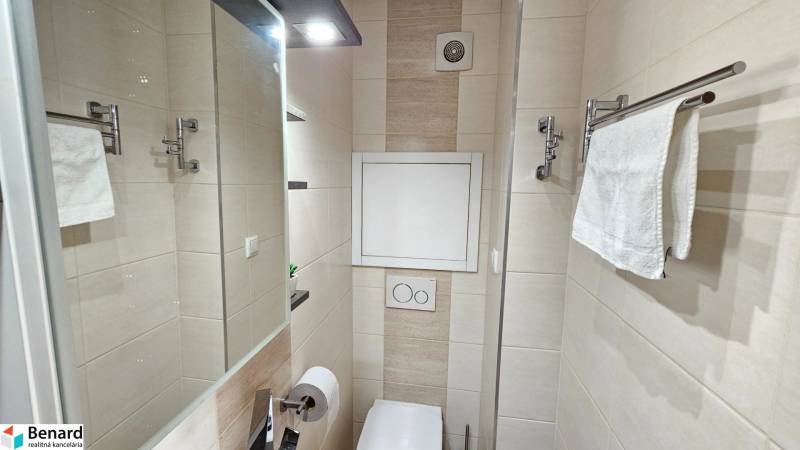A minimalist toilet with a white towel and a hanger in a studio apartment.