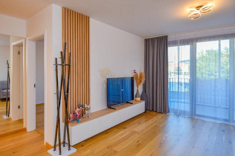 Living room in a 3-room apartment with a TV, glassed-in balcony, and wooden floor.