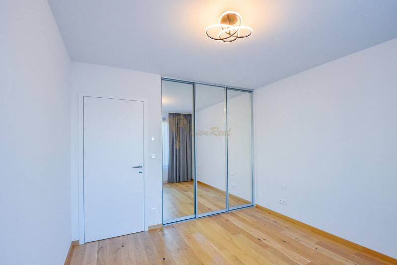 A room with a wooden floor, a mirrored wardrobe, and simple lighting in a 3-room apartment.
