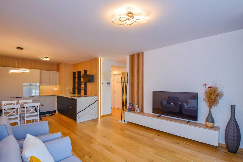 Living room with an open kitchen; wooden floor, dining table, television, 3-room apartment.