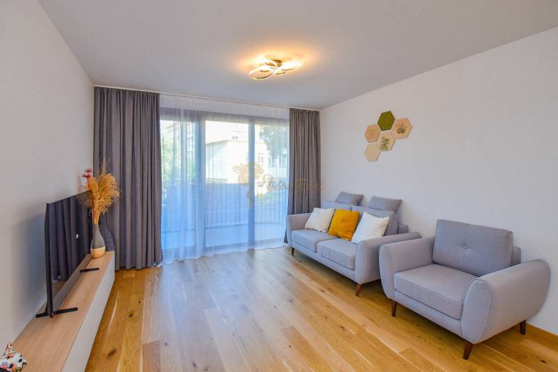Living room with a comfortable sofa, wooden floor, and a television in a 3-room apartment.