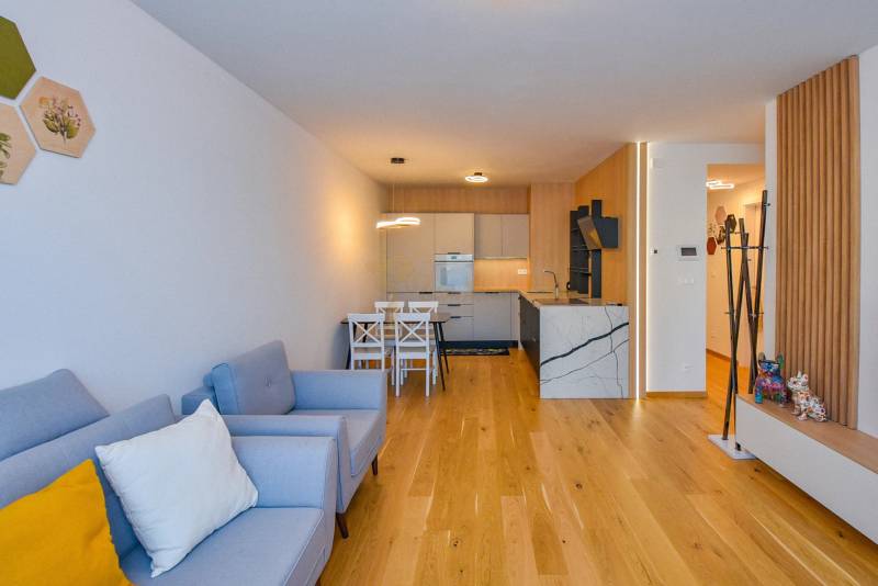 Living room in a 3-room apartment with a kitchen, light wooden floors, and comfortable seating.