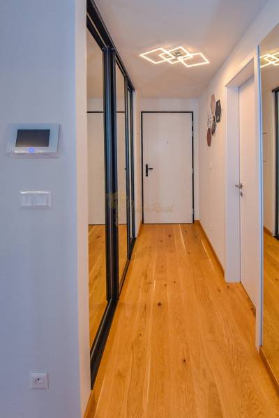 A hallway with mirrored wardrobes in a 3-room apartment, white walls, wooden floor.