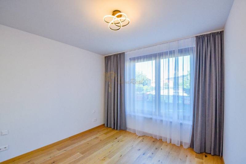 An unfurnished room with wooden flooring and curtains in a 3-room apartment.