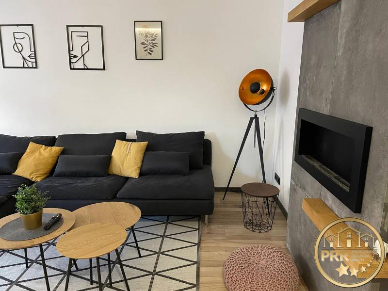 Living room in a 3-room apartment with a black sofa and decorative lighting.