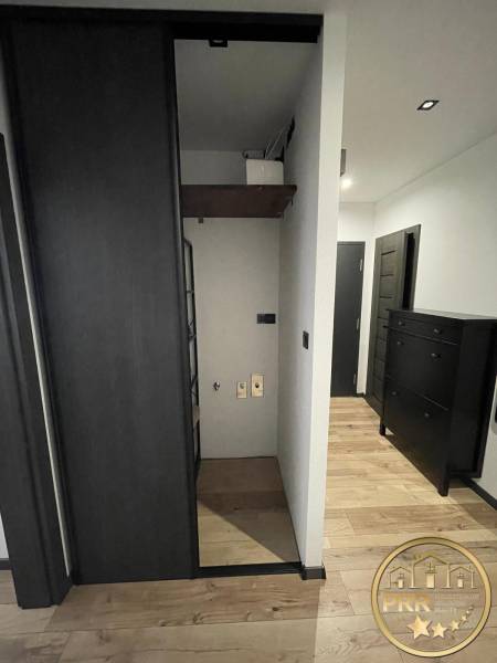 A hallway in a 3-room apartment with wooden flooring and dark furniture.