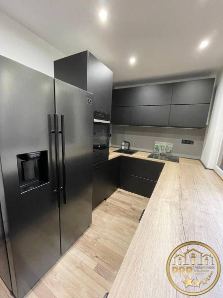 A kitchen in a 3-room apartment with black appliances and wooden flooring.