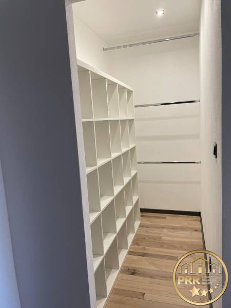 Built-in wardrobe with shelving system in a 3-room apartment, light wooden floors, white walls.