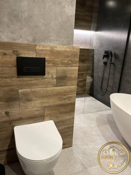A bathroom with a shower, bathtub, and wooden paneling in a 3-room apartment.