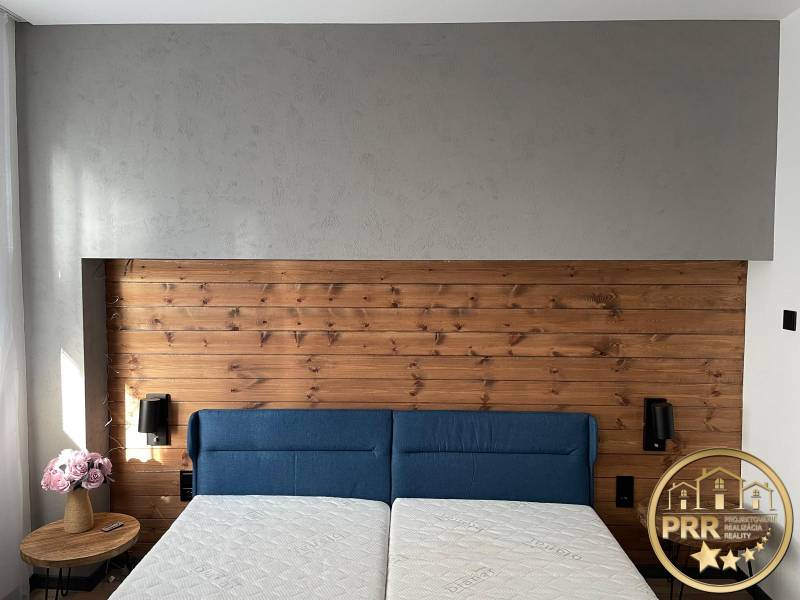 A bright bedroom in a 3-room apartment with a wooden headboard and a blue bed.