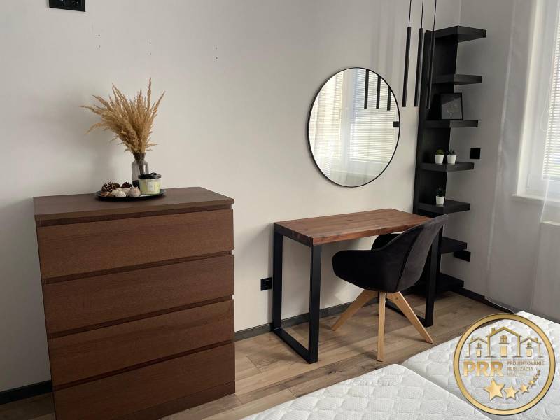 Bedroom with a dresser, mirror, and desk in a 3-room apartment.