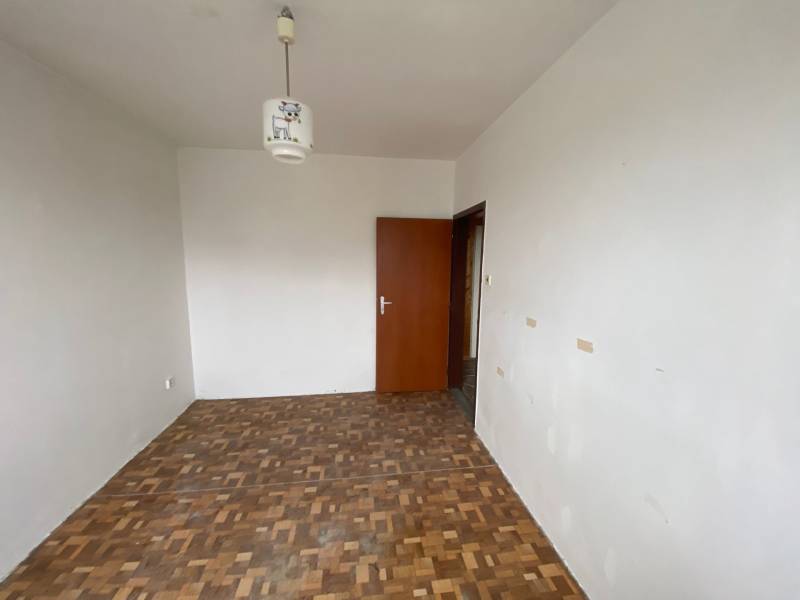 Empty room in a 3-room apartment with light walls and parquet flooring.
