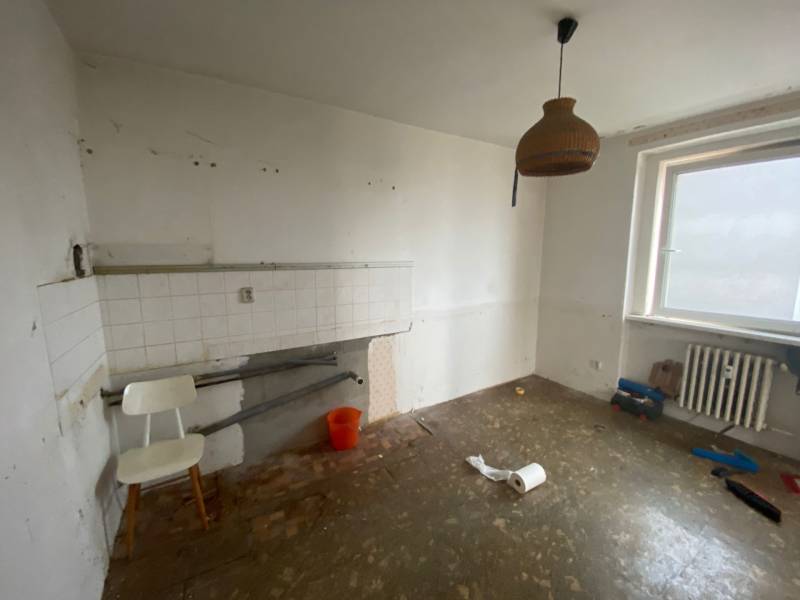 An empty kitchen with simple equipment in a 3-room apartment, white walls, radiator.
