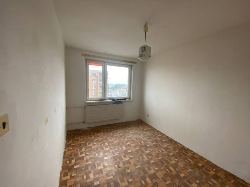 A room in a 3-room apartment with a wooden floor and a window with a view.