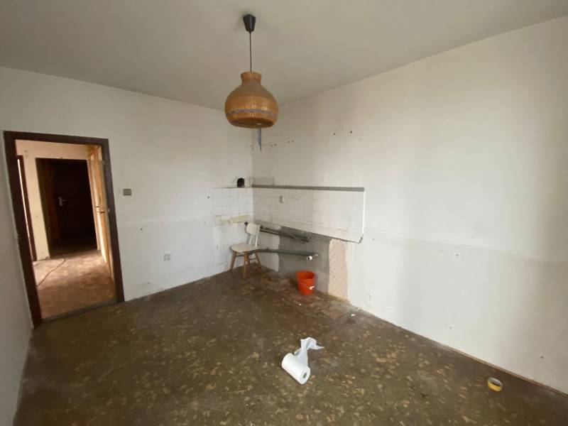 An empty kitchen in a 3-room apartment with an unusual chandelier and an unfinished floor.