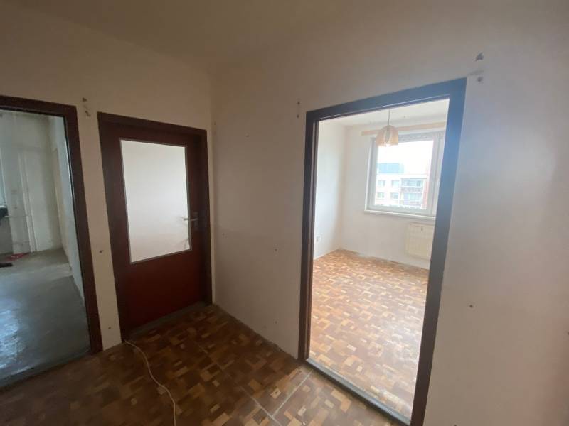 A hallway in a 3-room apartment with wooden doors and flooring.