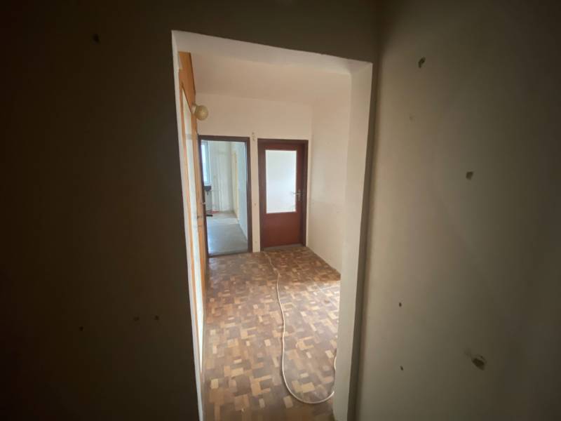 A hallway in a 3-room apartment with wooden flooring and two rooms.