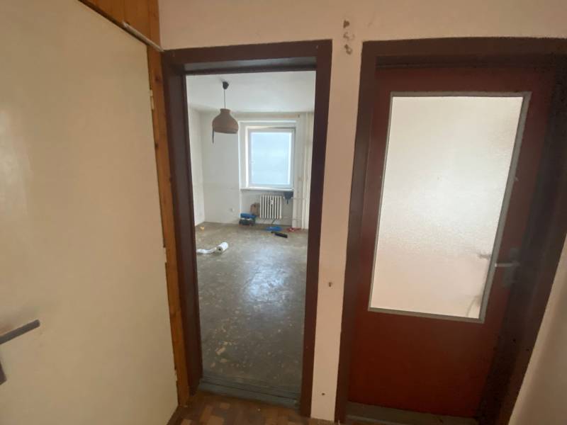 A room in a 3-room apartment with a bare floor and a window.