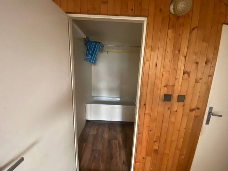 Bathroom in a 3-room apartment with wooden paneling and a bathtub.